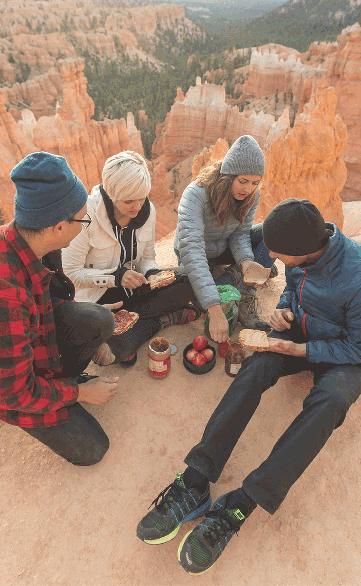 Group of friends enjoying a picnic outdoors on a rocky landscape, symbolizing adventure, friendship, and shared experiences